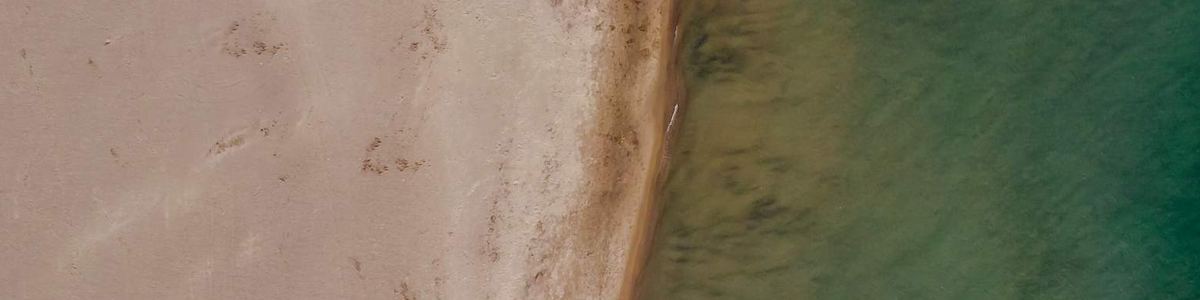 Luftaufnahme eines ruhigen Strands mit türkisgrünem Wasser